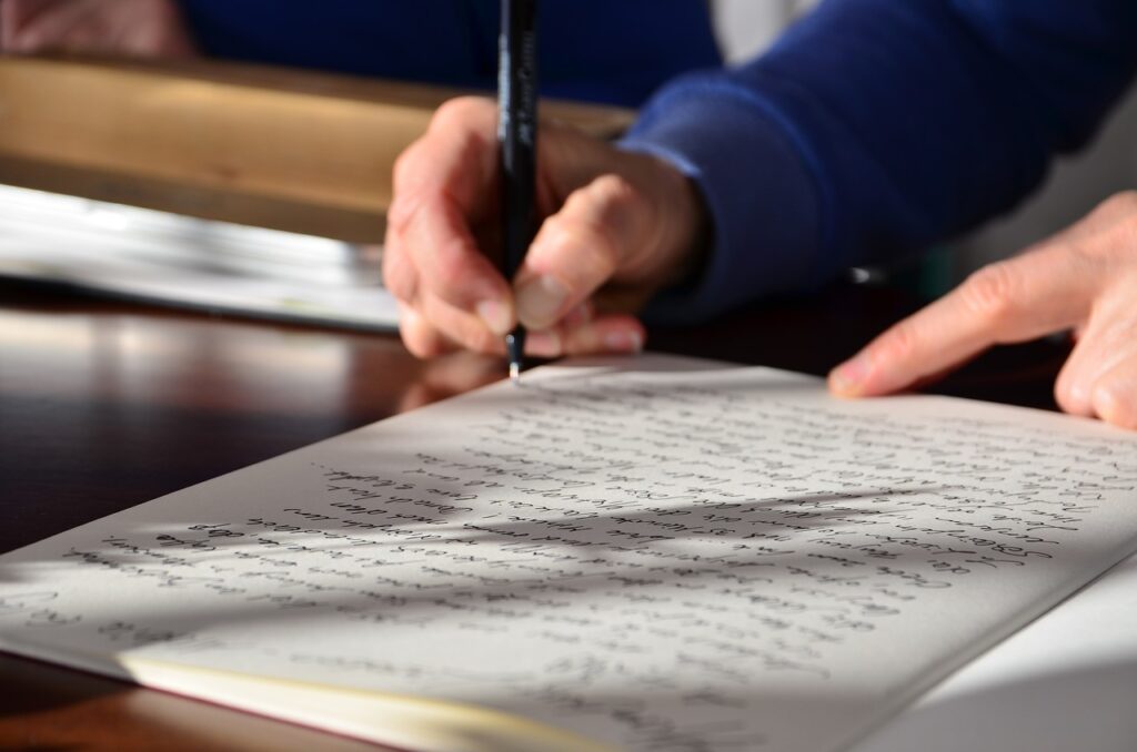 Close-up of a person writing notes in a notebook.